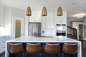 white kitchen with brass lamps and leather chairs