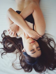 dark haired woman in black bra sleeping in bed