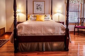 classic wooden bed in cosy bedroom with wooden floors