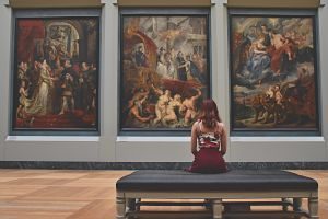 lady sitting on bench in front of paintings