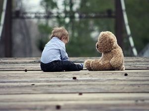 child and bear sitting on floor