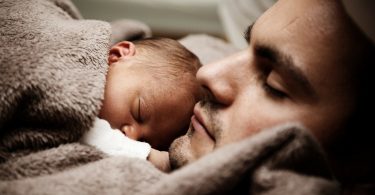 baby and father under brown blanket