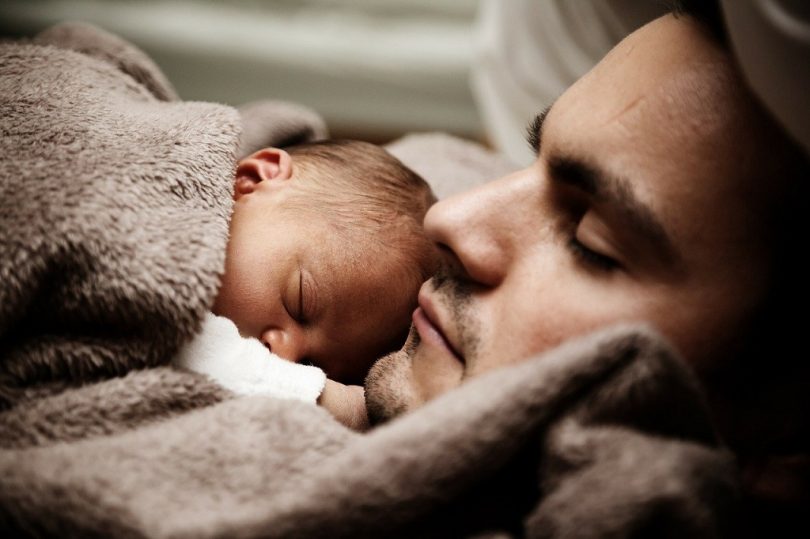baby and father under brown blanket