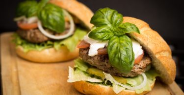 two hamburgers with basil on top