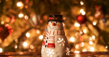 christmas tree with lights and snow man in front of it