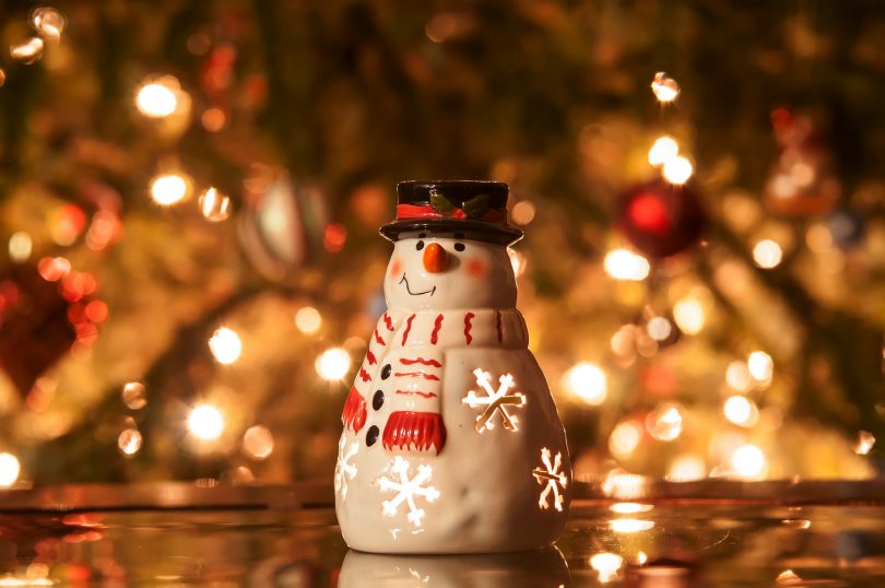 christmas tree with lights and snow man in front of it