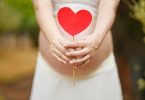 pregnant woman with red heart in front of her