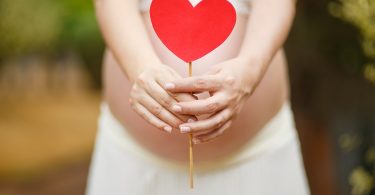 pregnant woman with red heart in front of her