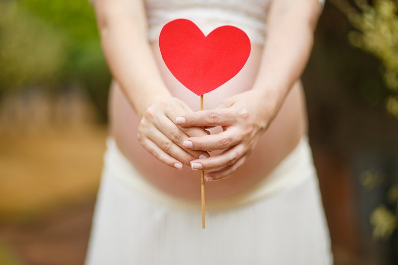 pregnant woman with red heart in front of her