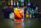 glass of vermouth with lemon and ice in it