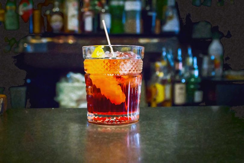 glass of vermouth with lemon and ice in it