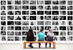 three people sitting in front of portraits in museum