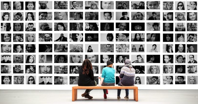 three people sitting in front of portraits in museum