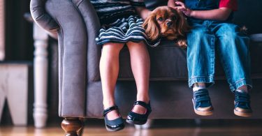 deux enfants avec un chien assis sur un canapé